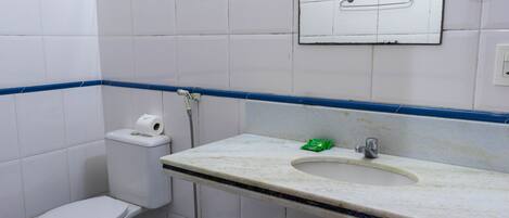 Een badkamer met toilet, wastafel en spiegel.