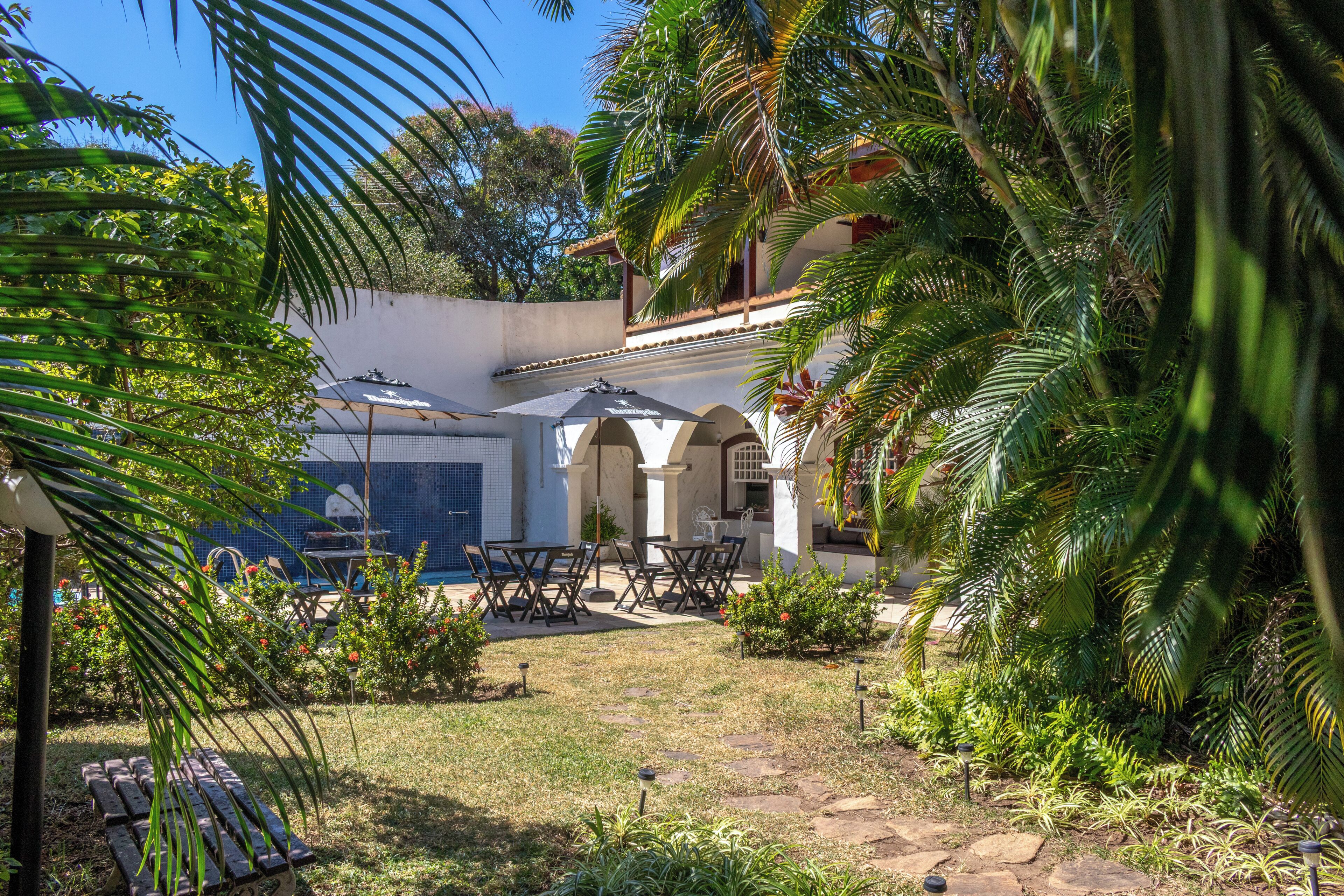Un patio con mobiliario exterior, piscina y abundante vegetación.