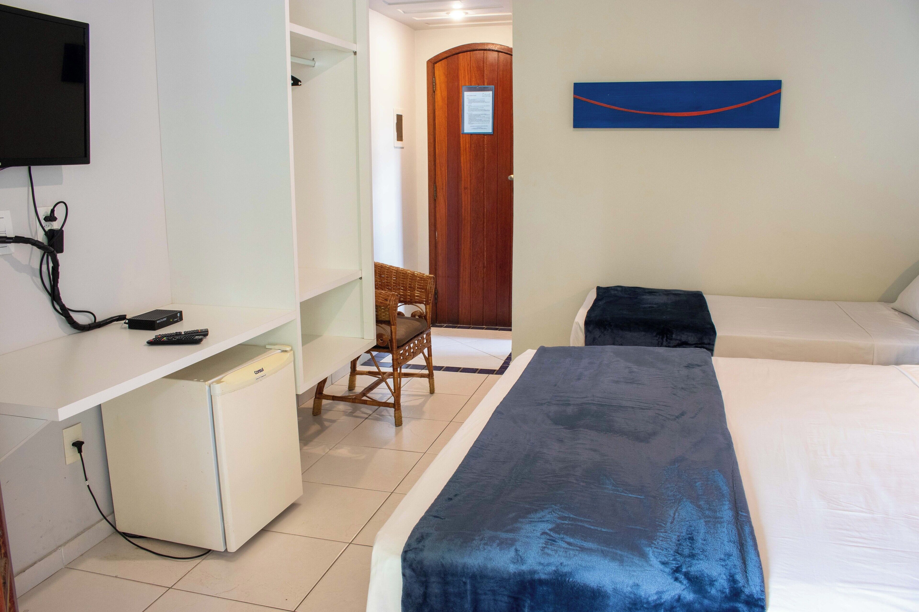 Une chambre d’hôtel comprenant un lit, un bureau avec un ordinateur, une chaise et un petit réfrigérateur.