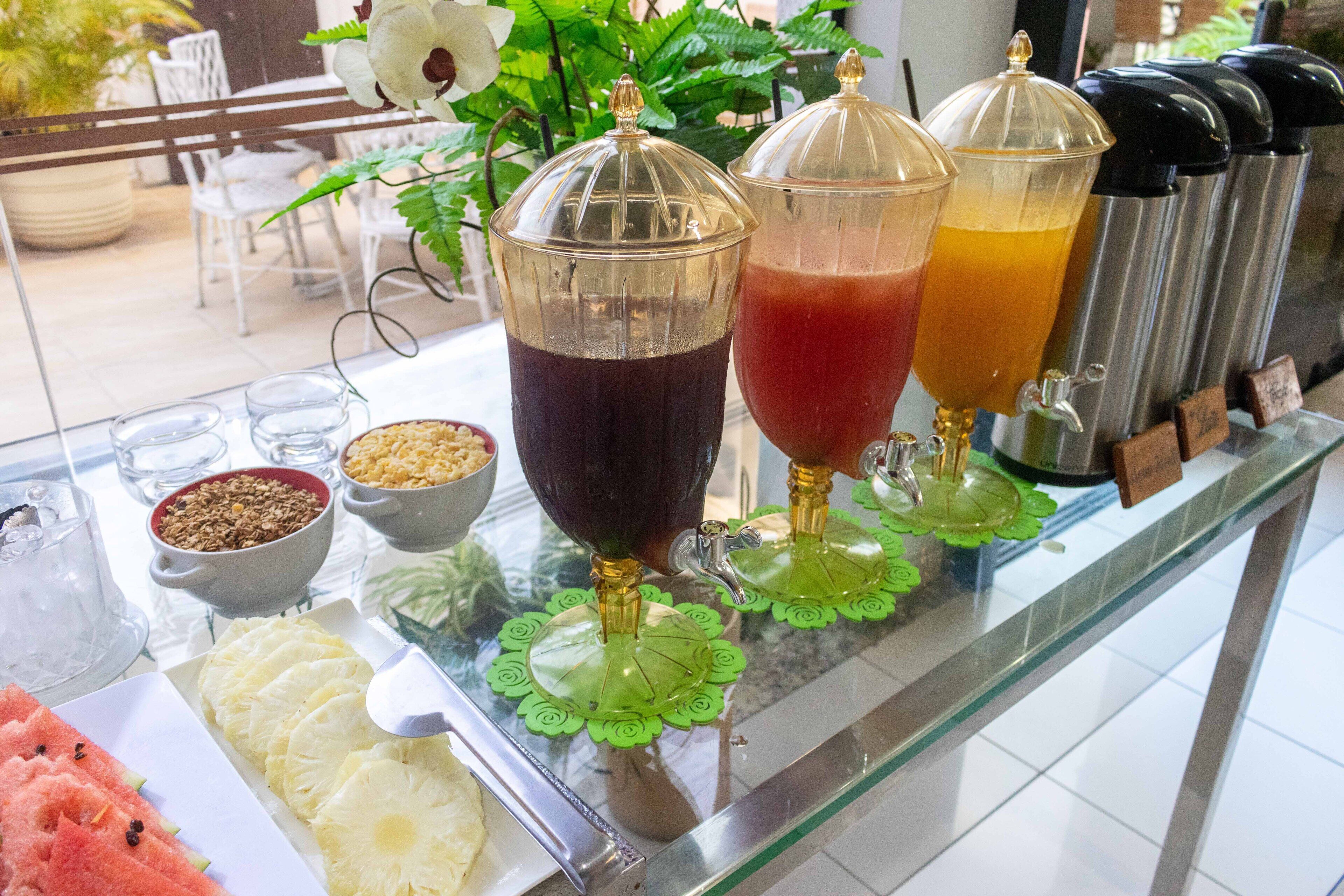 A beverage station with various drinks and a fruit platter.