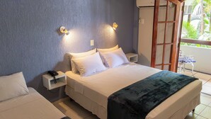 Une chambre à coucher avec un lit, des tables de chevet, un téléphone et une fenêtre donnant sur un paysage verdoyant.