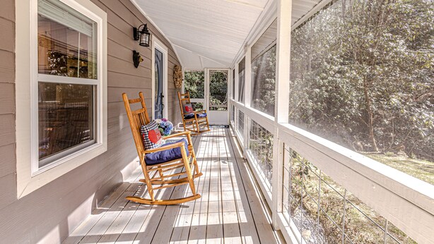 A covered porch with wooden rocking chairs and a view of trees. - "UNWIND BY THE WATER'S EDGE" Beautiful 2/1 Cabin w/ Hot Tub on Roaring Creek! (Bryson City)
