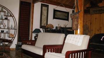 Una habitación con un sofá de madera, una mesita auxiliar, una lámpara y un estante con adornos.