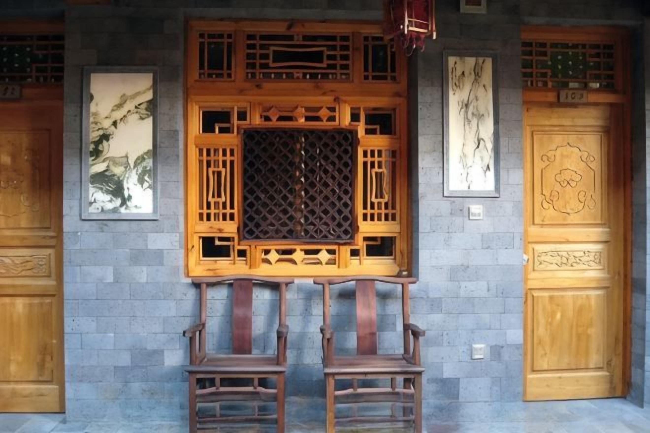 A traditional room with a wooden screen door, two wooden chairs, and a stone wall.