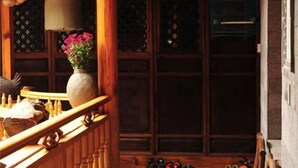 A wooden staircase with a hanging light fixture, a vase with flowers, and a birdcage. - Moonshine Inn (Dali City)