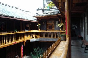 Un patio tradicional con balcones de madera, un jardín central y un edificio típico con tejado de baldosas.