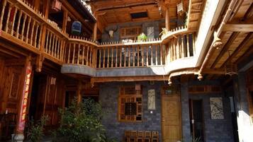 A traditional wooden building with a balcony, stone walls, and a door.