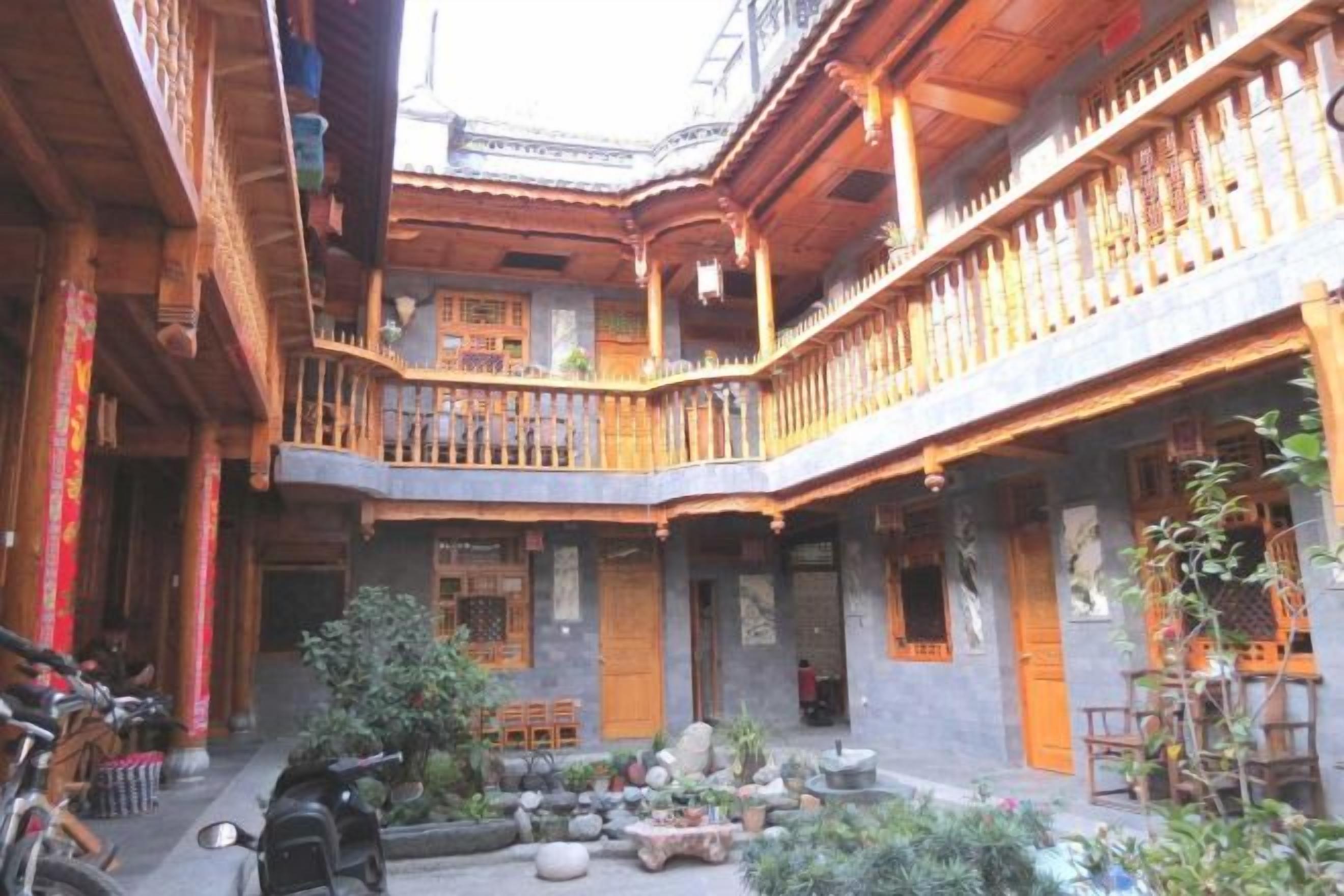 Un patio tradicional con balcones de madera, un área de descanso y plantas en macetas.