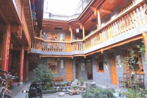 A traditional courtyard with wooden balconies, a seating area, and potted plants. - Moonshine Inn (Dali City)