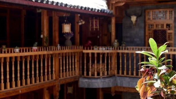 A traditional wooden building with a balcony, wooden railings, and a tiled roof. - Moonshine Inn (Dali City)