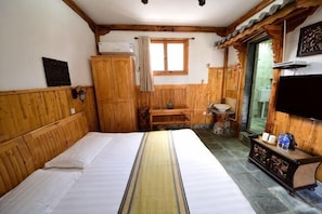 A room with a bed, wooden walls, a television, a sink, and a window.