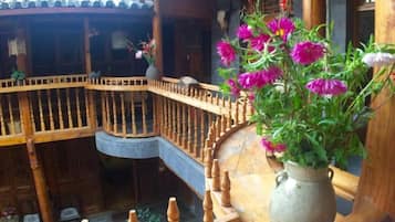 A wooden balcony with a railing, a vase with flowers, and a traditional tiled roof.