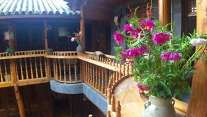 A traditional wooden building with a curved balcony and a large vase of flowers. - Moonshine Inn (Dali City)