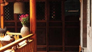 A wooden staircase with a railing, a vase with flowers, and a birdcage on the wall.