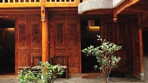 A traditional wooden building with intricate carvings on the doors and a balcony with wooden railings. - Moonshine Inn (Dali City)