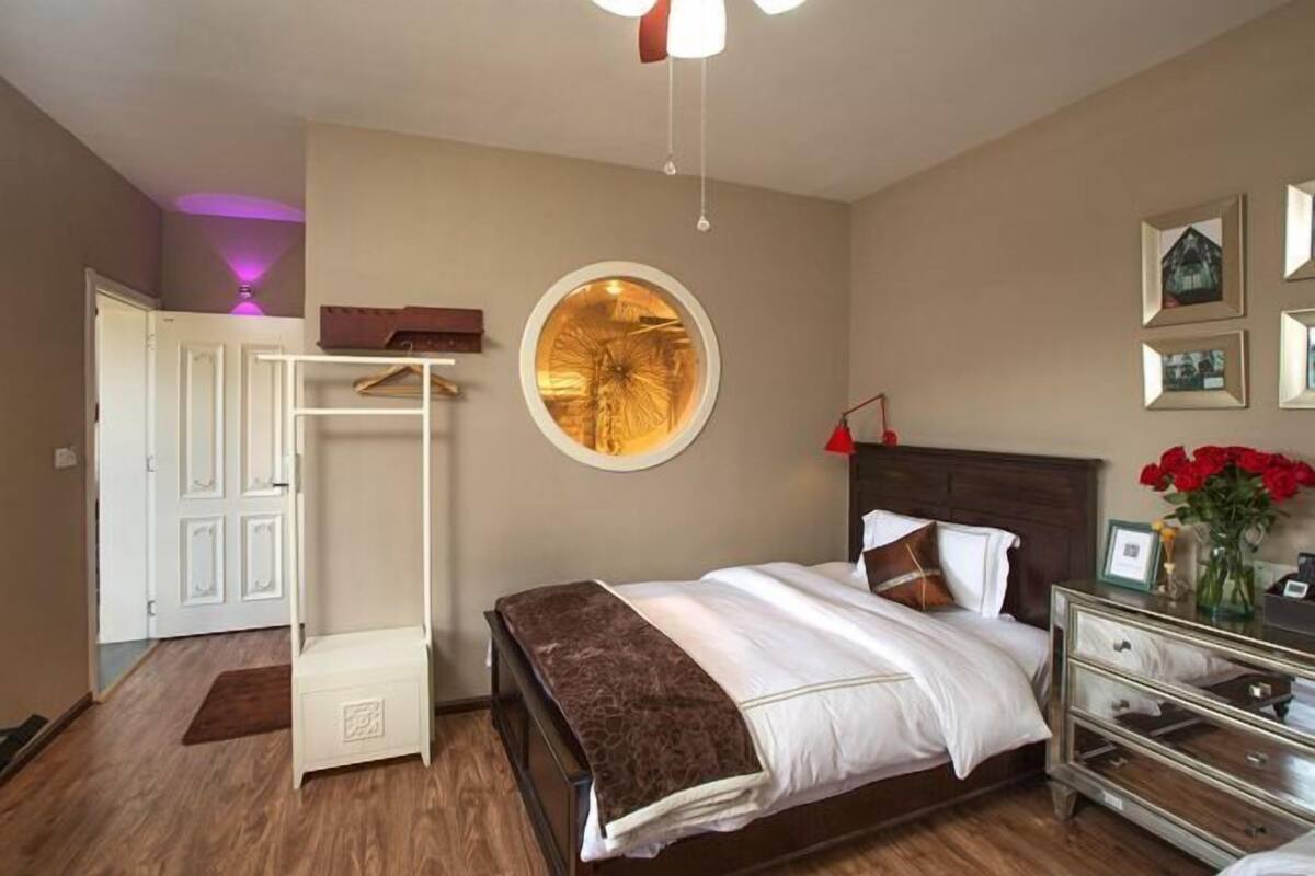Un dormitorio con cama, armario, espejo y un reloj de pared.