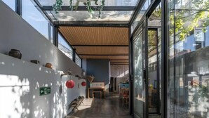 A corridor with a wooden ceiling, glass walls, and a view of the outside. - Qingtian Yashe Inn (Tengchong)