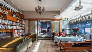 A spacious room with a large bookshelf, a dining area with a table and chairs, and a view of the outside through a sliding door. - Qingtian Yashe Inn (Tengchong)