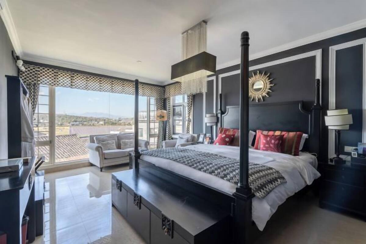 Un dormitorio moderno con una cama grande, vistas de la ciudad y un balcón.
