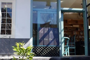 A building entrance with a glass door, a metal gate, and a small plant. - Qingtian Yashe Inn (Tengchong)