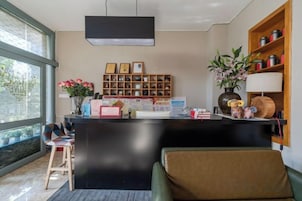 Una moderna zona de recepción con un mostrador negro, una estantería de madera y un ventanal que proporciona luz natural.