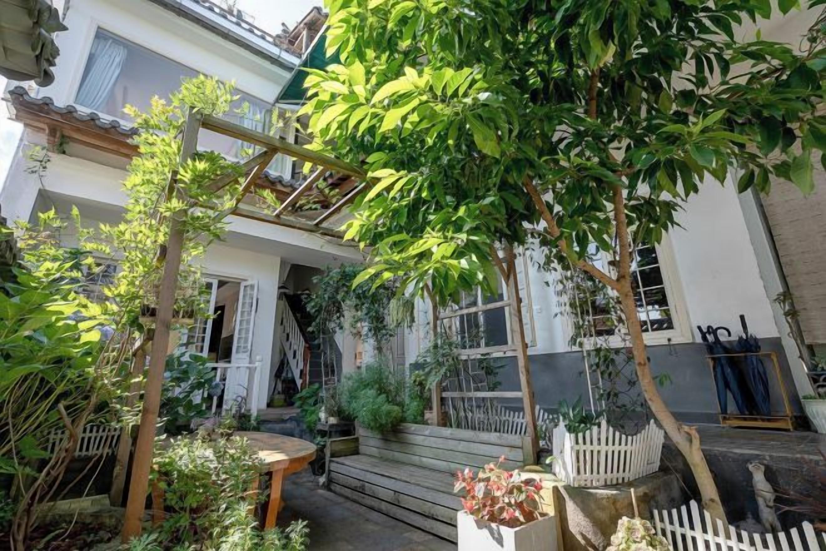 A courtyard with a wooden pergola, a small table, and a white picket fence.