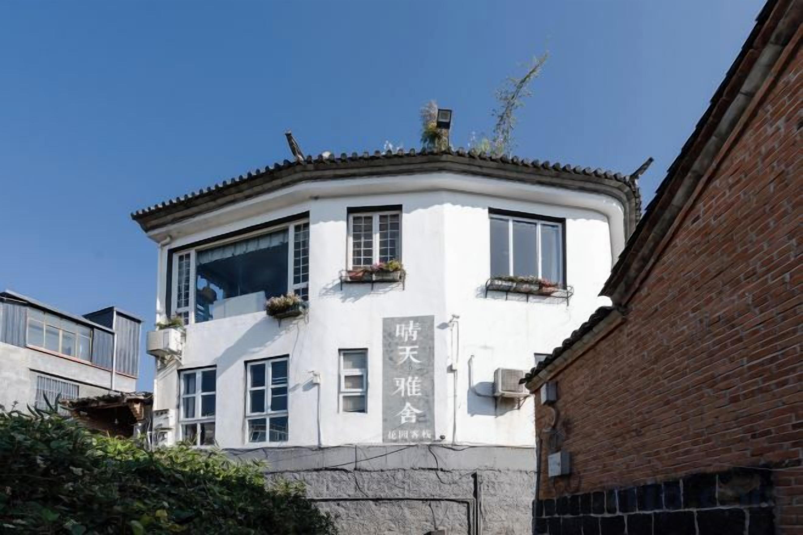 Un edificio blanco con techo curvo, varias ventanas y un letrero con caracteres chinos.