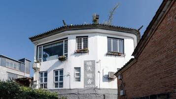 Un edificio blanco con techo curvo, varias ventanas y un letrero con caracteres chinos.