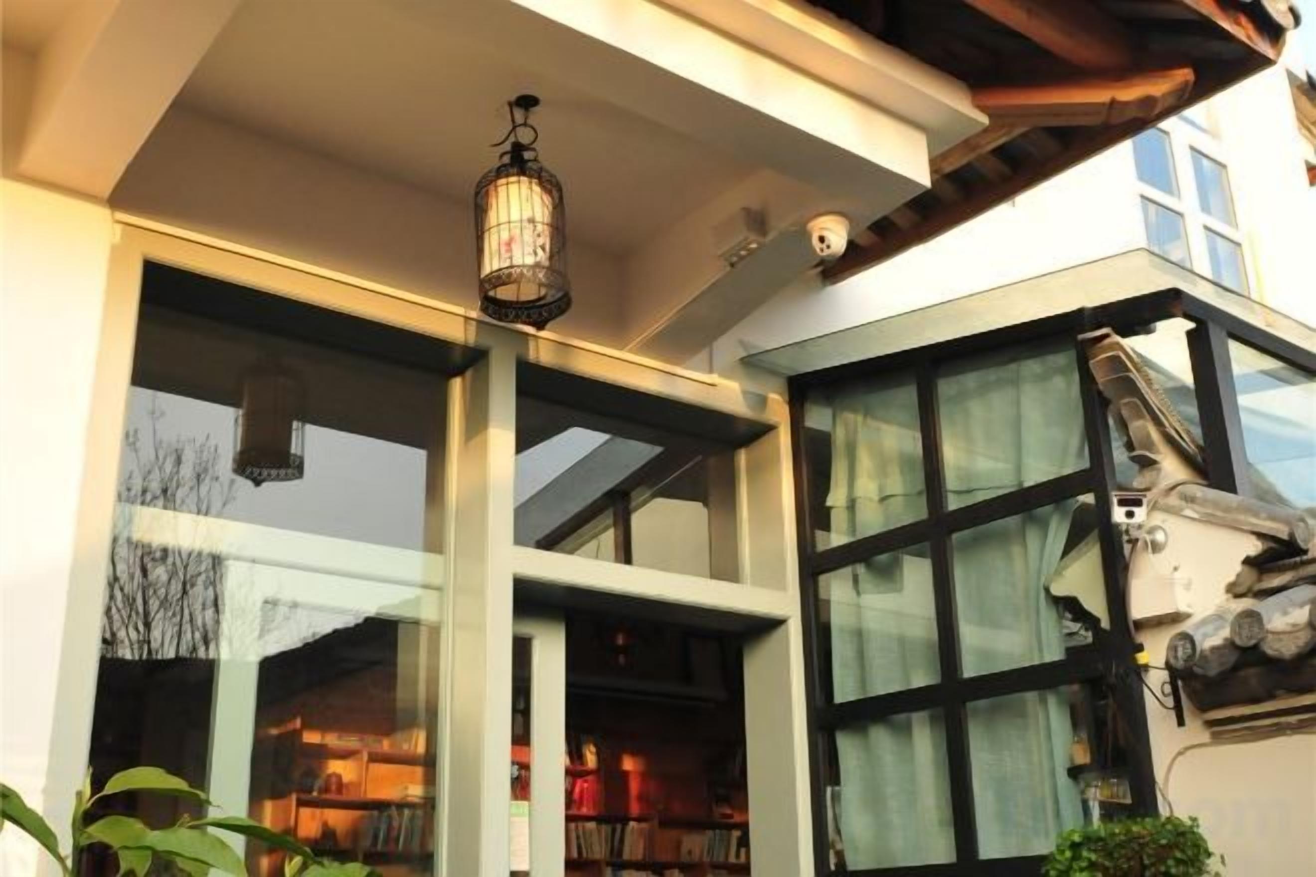 A modern building with large windows, a hanging light fixture, and a visible staircase.