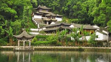 A traditional Chinese building complex with multiple structures, including a pagoda, situated by a body of water.