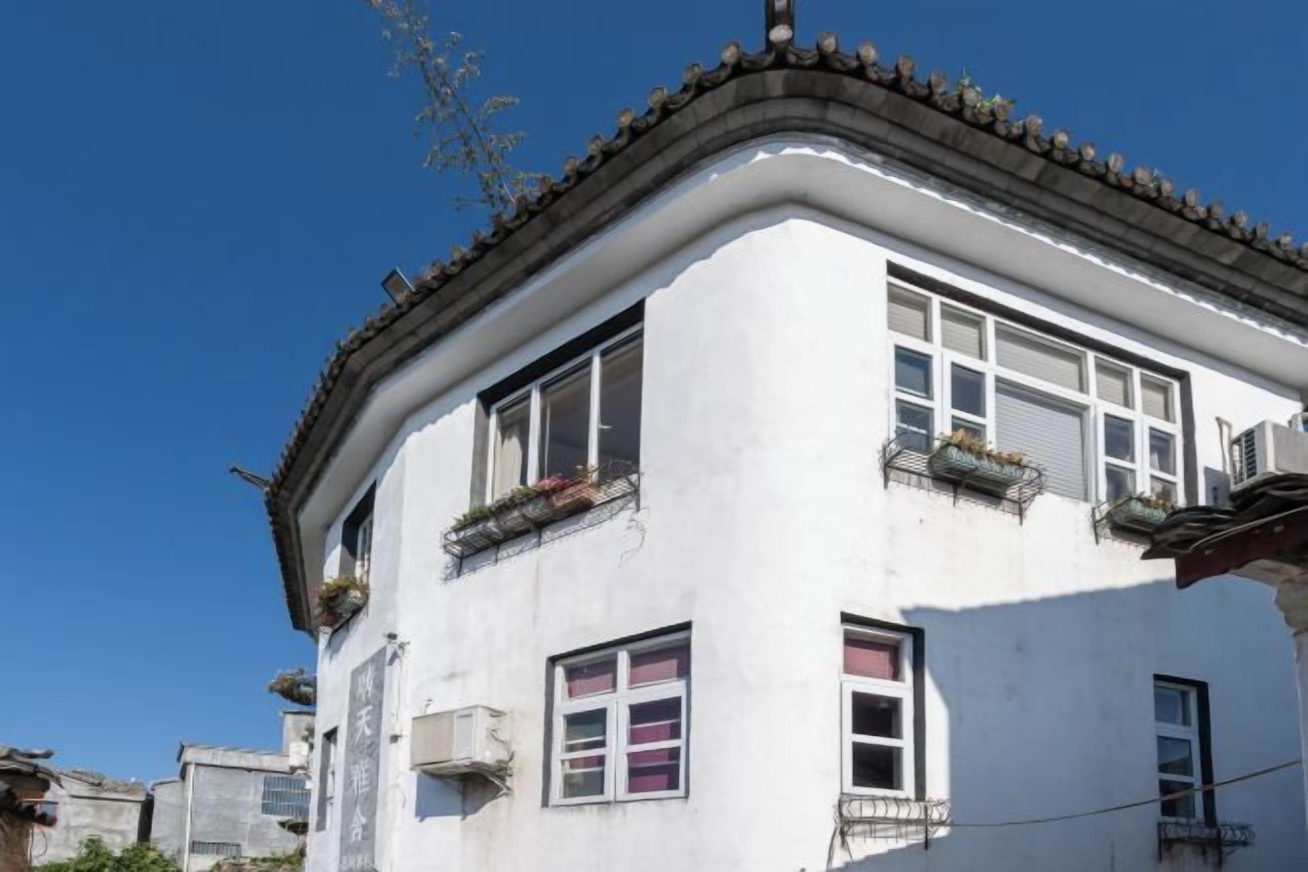 A corner building with multiple windows, some with balconies, and a clear blue sky in the background.