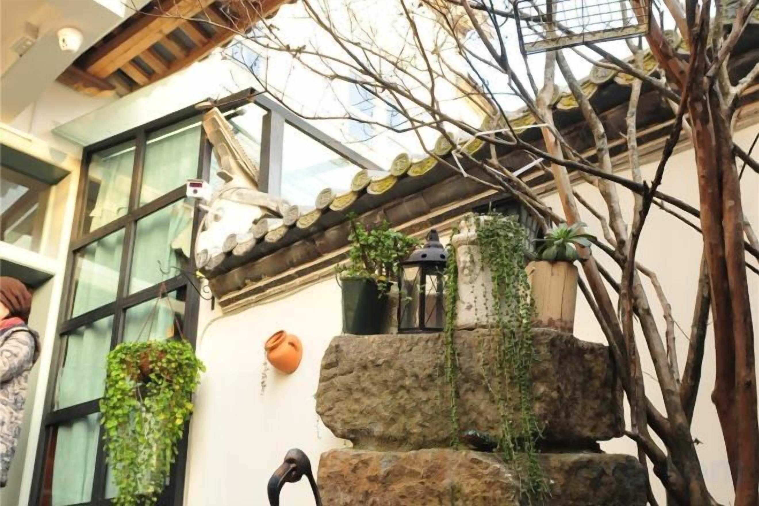 Um edifício tradicional com telhado de azulejos, paredes de pedra e plantas pendentes.