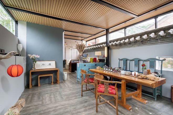 Un comedor con una mesa y sillas de madera, un banco y un muro decorativo.