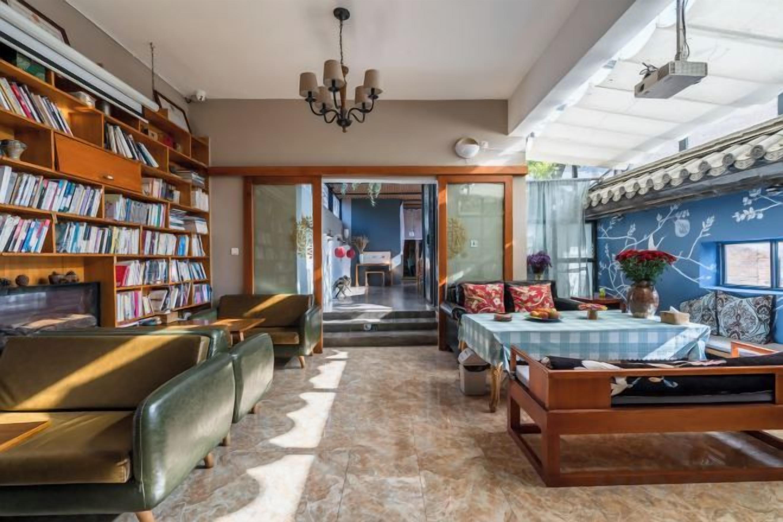 A spacious living area with a large bookshelf, a dining table, and a comfortable seating arrangement.