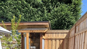 A wooden shed with a door, a small garden with various plants, and a gravel path. - Modern Vintage Camper w/ Peaceful Private Yard (Eugene)