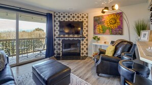 Ein Wohnzimmer mit Kamin, einer Couch, einem Couchtisch und einem an der Wand befestigten Fernseher.