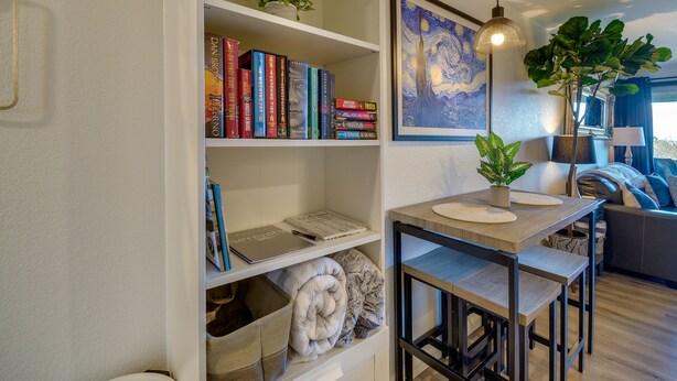 Ein modernes Wohnzimmer mit Bücherregal, Esstisch und einem Gemälde an der Wand.