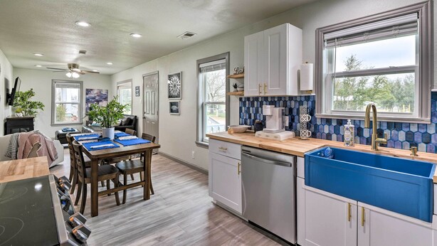 A modern kitchen with a blue sink, wooden dining table, and white cabinets. - Lake Granbury Getaway ~ 1 Block to Waterfront (Granbury)