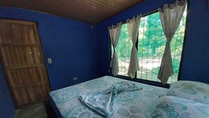 Ein Zimmer mit einem Bett, einer Holztür und einem Fenster mit Vorhängen.