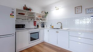 Una cocina moderna con armarios blancos, un microondas, un horno, un lavamanos y una encimera con varios objetos.