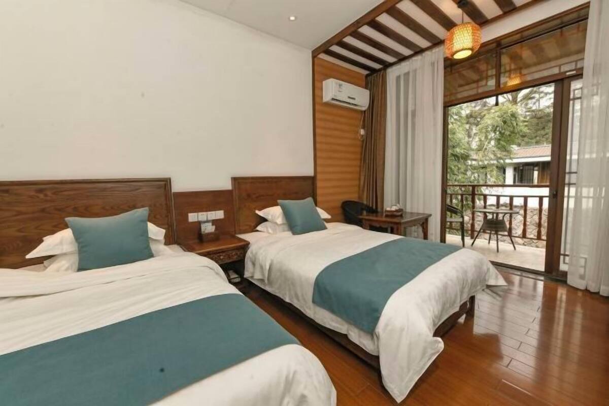 Habitación de hotel con dos camas, un balcón y techo de madera.