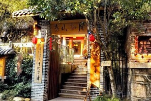 A traditional building with a staircase leading to a wooden door, surrounded by greenery. - Zhoujia Shanfang Family Hostel (Wuyishan)