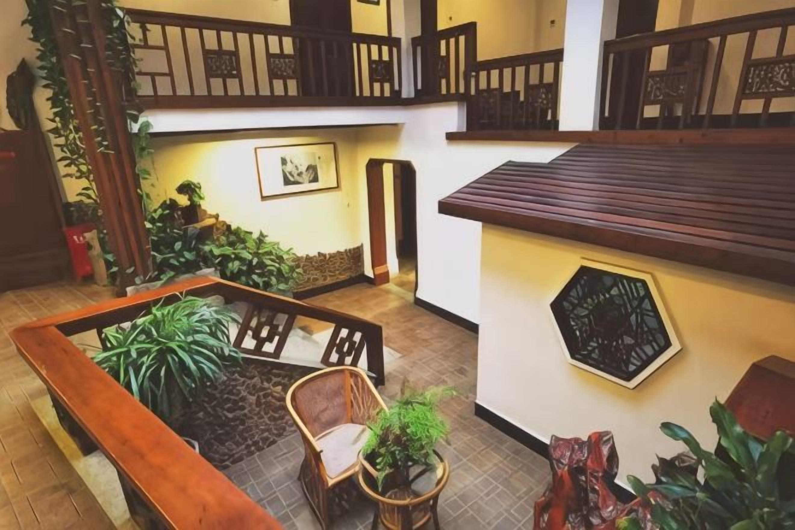 A spacious indoor area with a wooden bench, chairs, and potted plants.