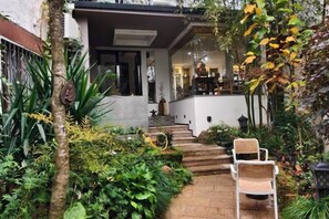 A modern house with a garden pathway leading to a white chair. - Zhoujia Shanfang Family Hostel (Wuyishan)