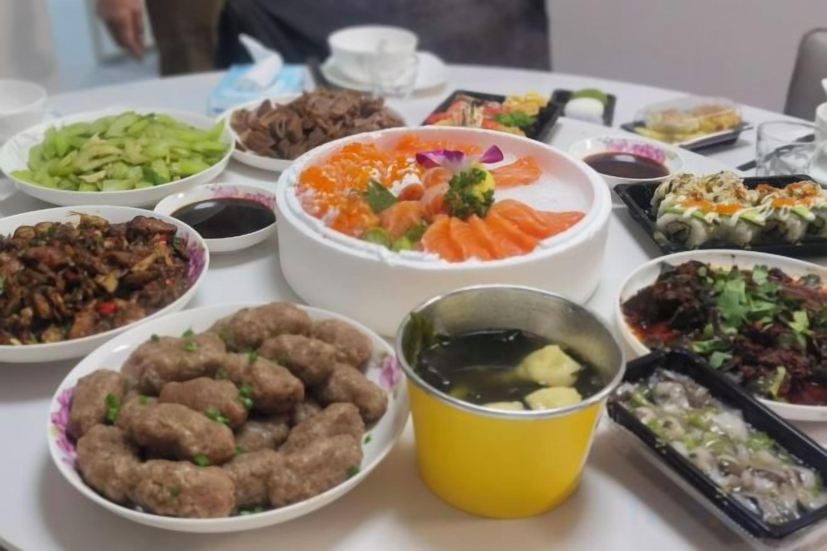 A table with various dishes, including a central bowl of food, side dishes, and a small bowl of soup.