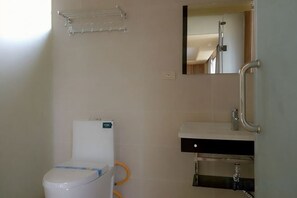 A bathroom with a toilet, sink, and mirror. - Laozheng Homestay (Yangshuo)