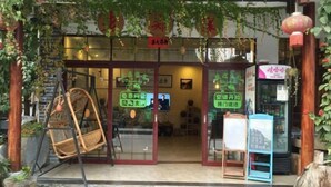A restaurant entrance with a swing chair, glass doors, and a signboard. - Laozheng Homestay (Yangshuo)