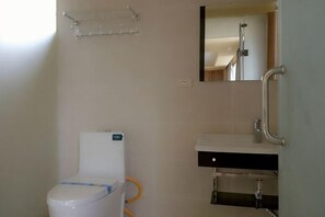 A bathroom with a toilet, sink, mirror, and shower. - Laozheng Homestay (Yangshuo)