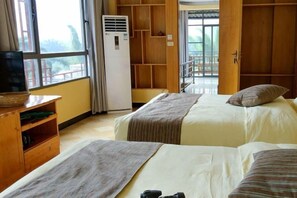 A hotel room with two beds, a television on a wooden stand, a wardrobe, and a balcony with a view. - Laozheng Homestay (Yangshuo)