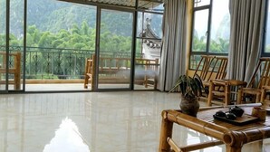 A spacious room with large windows, a polished floor, and traditional wooden furniture. - Laozheng Homestay (Yangshuo)